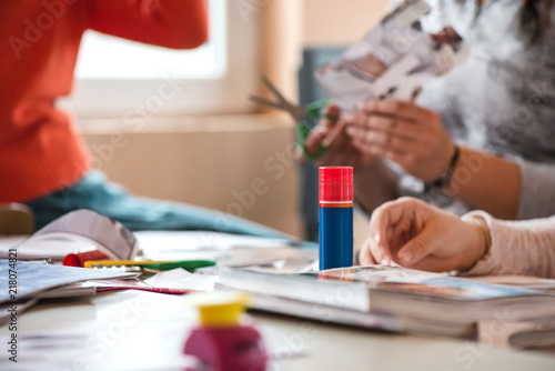 Creative workshop for kids. Little girls gluing cut out shapes and characters from magazines on white paper. Concept of art, crafts, kids having fun. Making collages and creating stories. Messy desk 