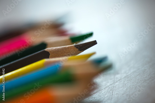 Pile of sharp coloured drawing pencils on table. Rainbow colors red, yellow, blue, green, purple. Concept of art, crafts and kids having fun