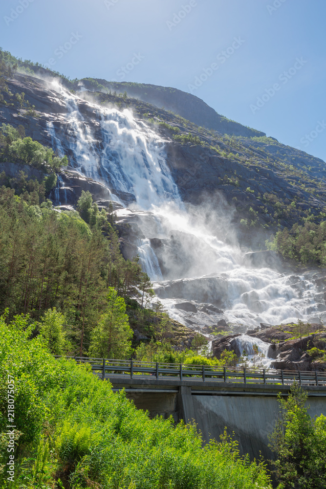 Fototapeta premium The Langfossen falling into the fjord with the main road in front of it
