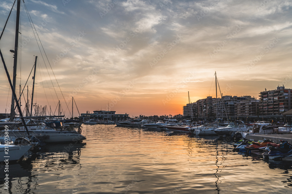 boats in port moored at sunset with the sun in front