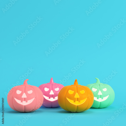 Four colorful halloween pumpkins, jack o lantern on bright blue background in pastel colors