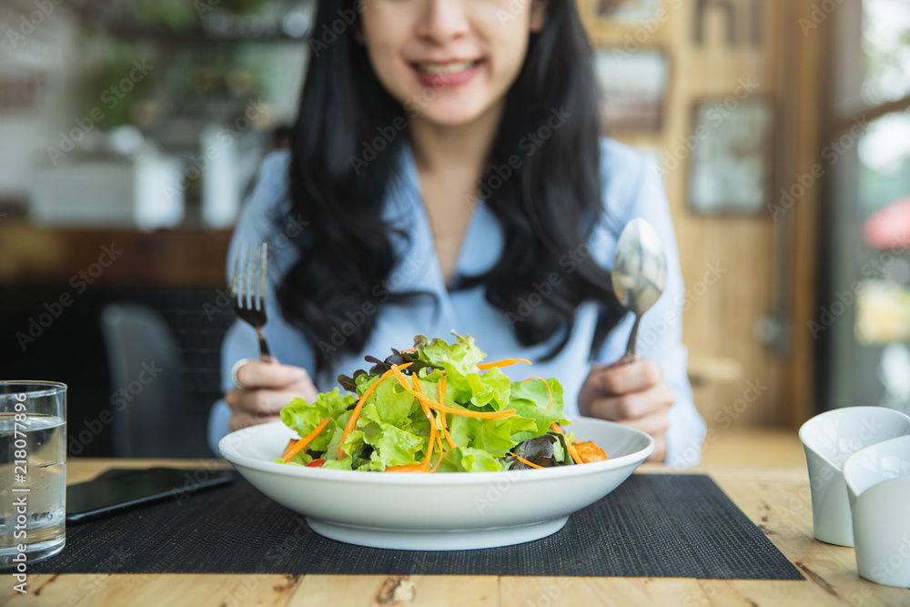 Happy woman eating healthy salad sitting on the table . Beautiful girl eating healthy food. Diet and healthy food concept Happy woman eating healthy salad sitting on the table . Beautiful girl eating healthy food. Diet and healthy food concept