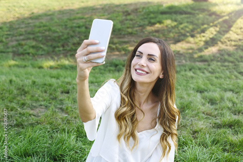 Portrait of young woman making selfie photo in park