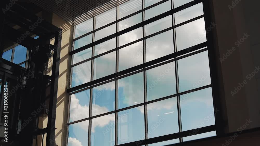 Clouds float outside the window buildings, the elevator rises and goes down (Time Lapse)