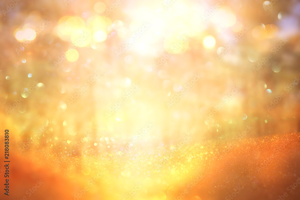 blurred abstract photo of light burst among trees and glitter golden bokeh lights.