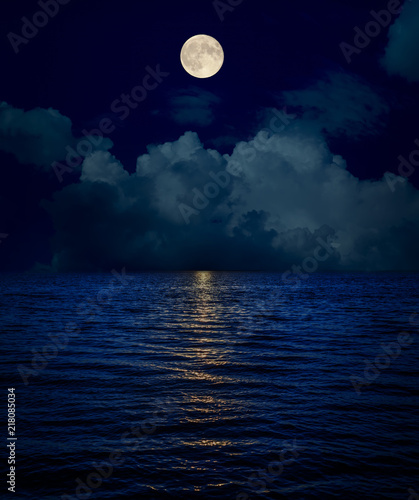 full moon over clouds and dark water with reflections