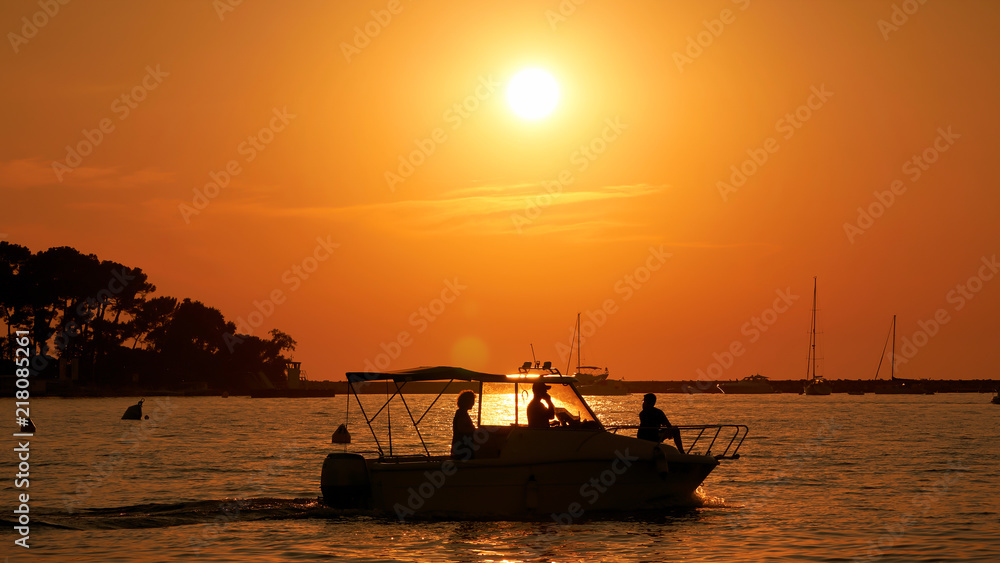Sonnenuntergang mit Booten an der Küste der Stadt Porec in Kroatien. Im Hintergrund befindet sich die Insel Sveti Nikola
