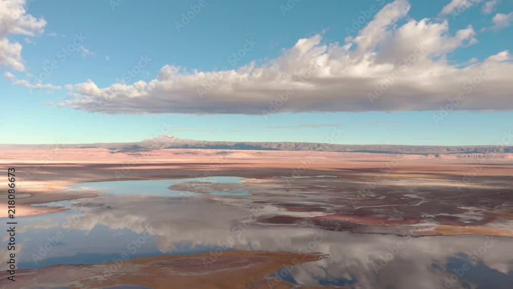 Cinematic aerial view of salt lake in Atacama desert Chile. Drone flying backwards over flat water with sky and cloud reflections from surface. Valle de la Luna. Cinematic aerial view of salt lake in Atacama desert Chile. Drone flying backwards over flat water with sky and cloud reflections from surface. Valle de la Luna.