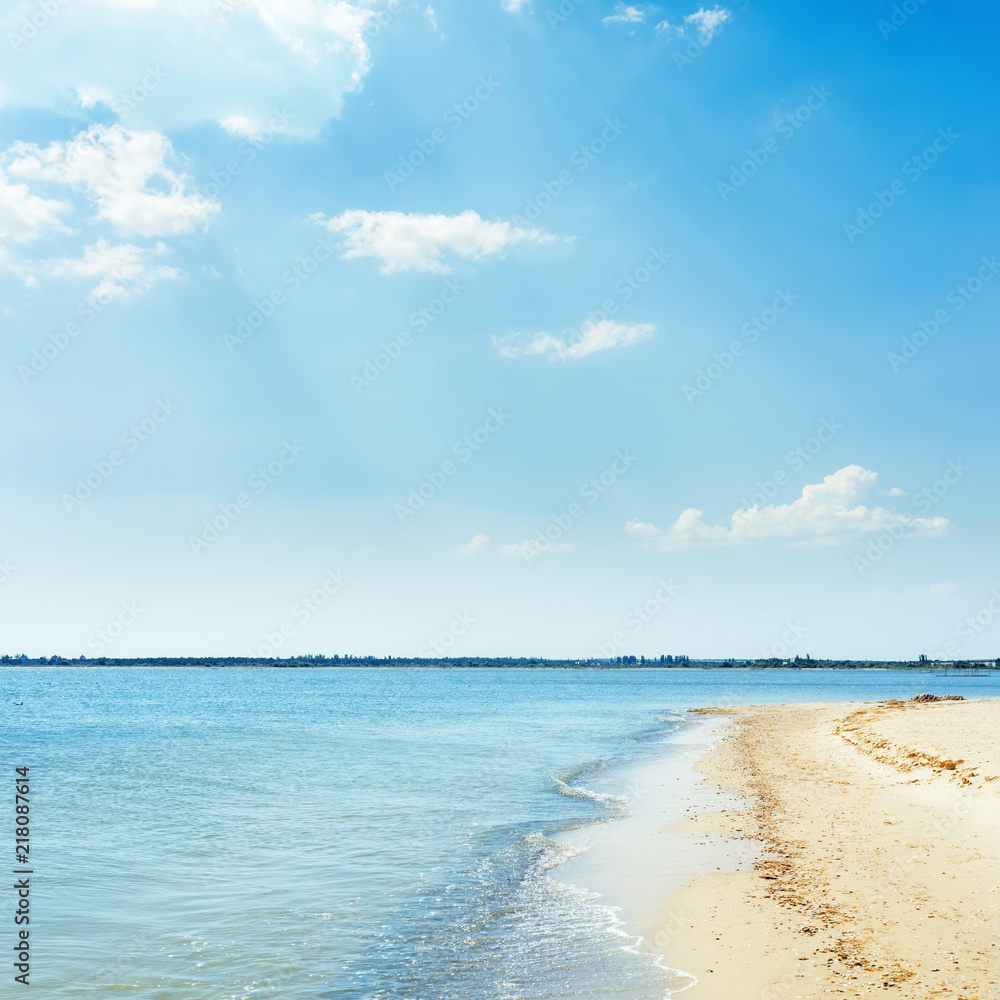 blue sea and yellow sand under blue sky with clouds