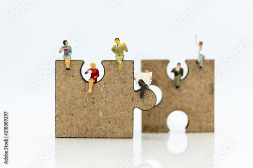 Miniature people : businessman sitting on jigsaw puzzle pieces . Image use for solve, finding solution, business vision concept.