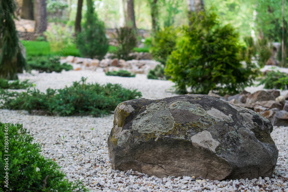 An artificial rock garden, a large and heavy stone among the many white small stones in the open-air design garden An artificial rock garden, a large and heavy stone among the many white small stones in the open-air design garden