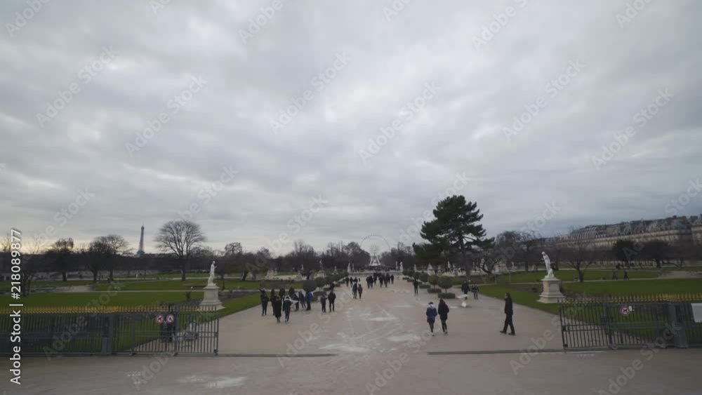 People walk along the entrance to the Tuileries Garden (Jardin Des Tuileries) in Paris during a cloudy day People walk along the entrance to the Tuileries Garden (Jardin Des Tuileries) in Paris during a cloudy day
