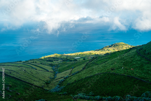 Fototapeta Naklejka Na Ścianę i Meble -  View to the green fields and coastline of Corvo Island in Azores with some clouds