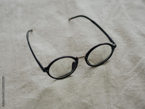 Eyeglasses on white bed in the morning.