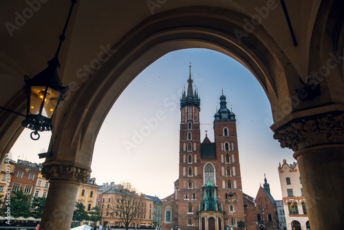 Beautiful view of Saint Mary's Basilica from Cloth Hall building Sukiennice. Main market square in Krakow, Poland. Passage of the gothic hall with columns.