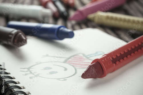Back to school concept. Still life close up of multicolor crayons with cute cartoon picture freehand drawing kid style on wood table.