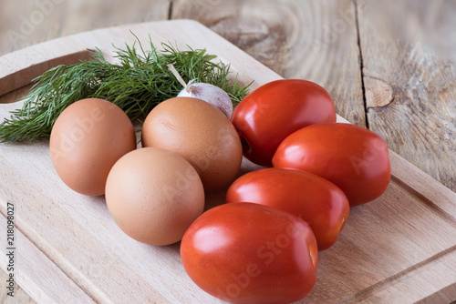 Tomatoes, eggs, garlic and dill on a cutting board