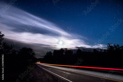 Light trail of a passing car on a rural road at night.