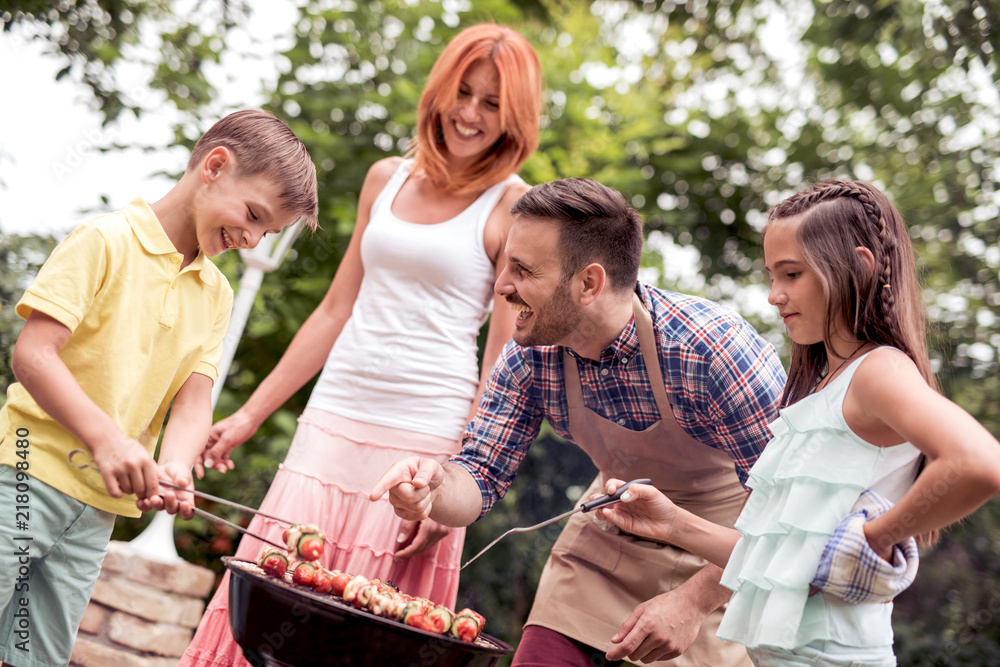 Fototapeta premium Young family having barbecue party in garden
