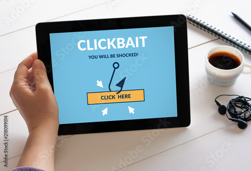 Hand holding digital tablet computer with clickbait concept on screen. All screen content is designed by me