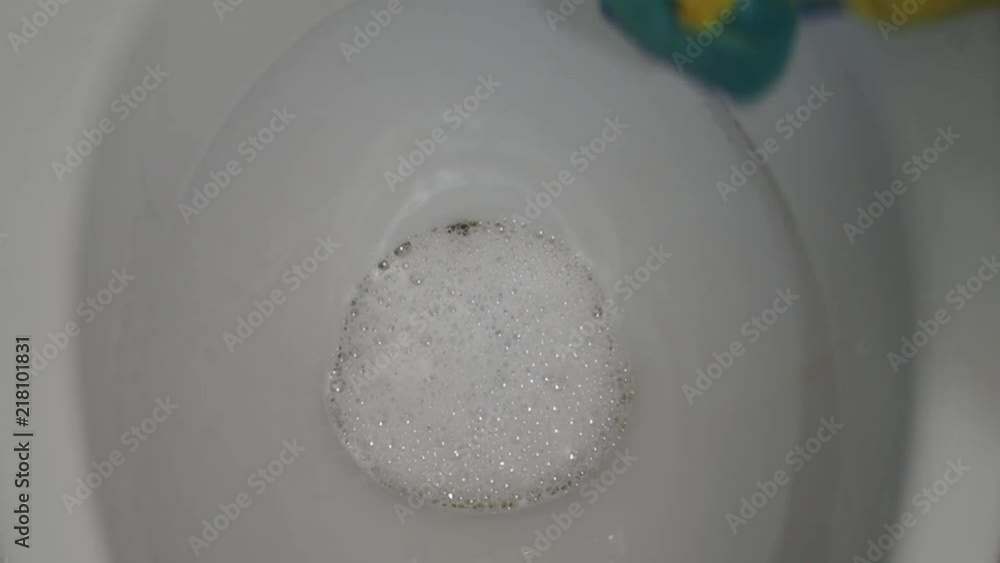 The woman washes with a bast an internal part of a toilet bowl. The woman washes with a bast an internal part of a toilet bowl.