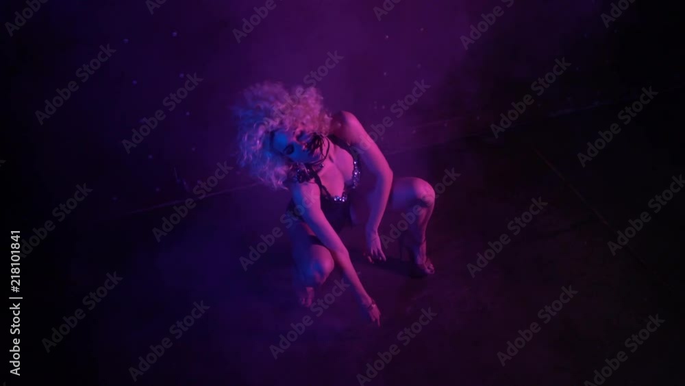 Attractive young woman with curly blond hair wearing lingerie dancing in the dark room. Tilt up slow motion medium shot Attractive young woman with curly blond hair wearing lingerie dancing in the dark room. Tilt up slow motion medium shot