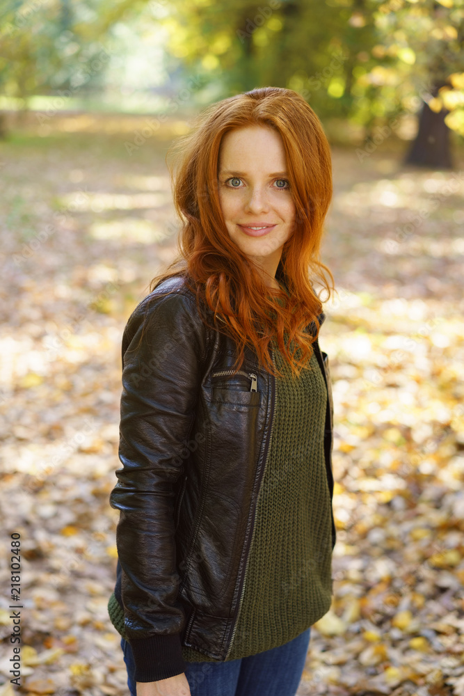 Red-haired woman standing in park on autumn day Red-haired woman standing in park on autumn day