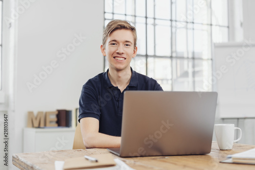 Fotografie, Obraz junger auszubildender sitzt im büro vor dem laptop