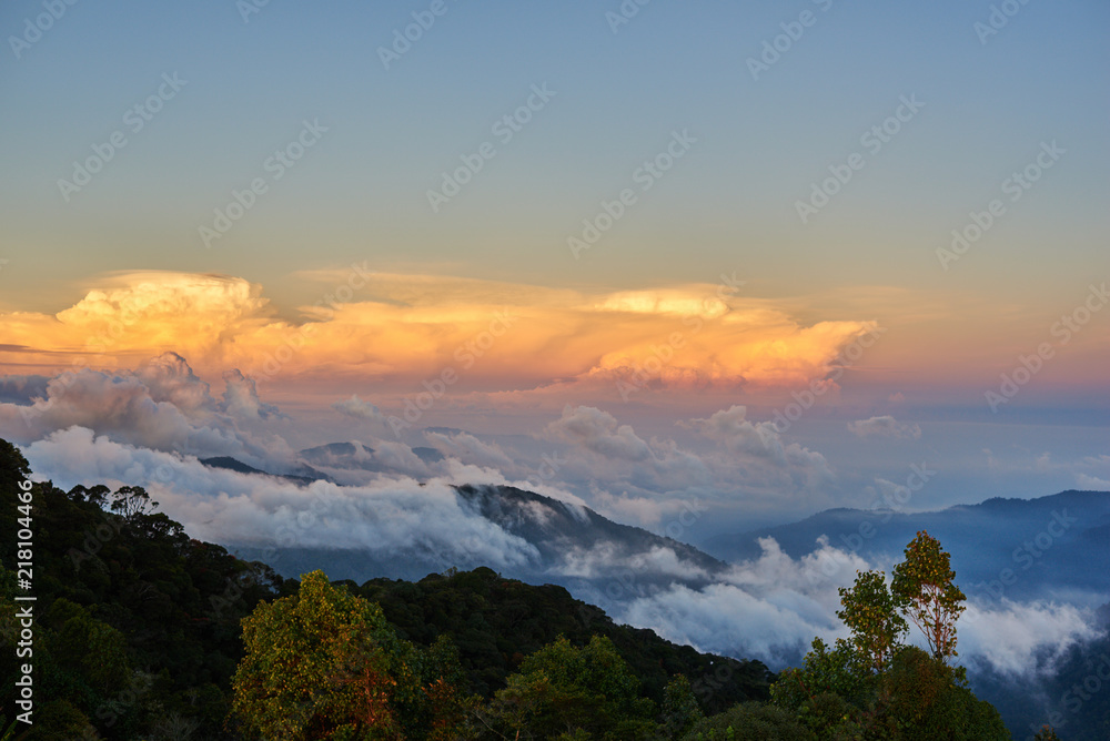 Picturesque mountain valley filled with curly clouds at sunrise.