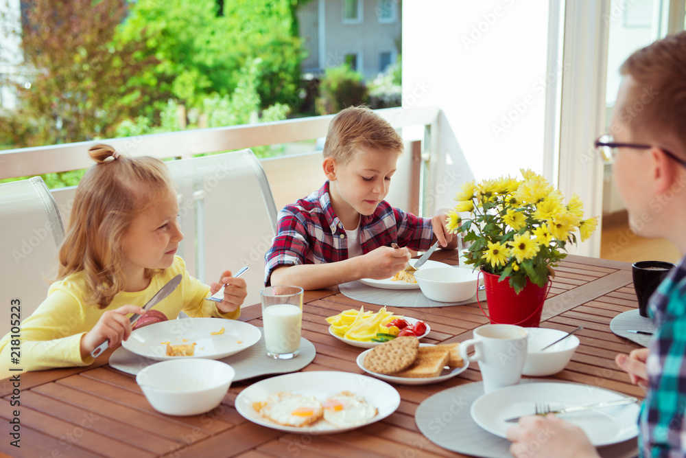 Happy young family having fun during breakfast on terrasse at home