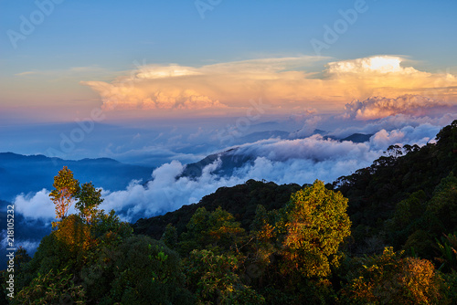 Mountains during sunset. Beautiful natural landscape in the summer time. A multicolored mist covered the hills. Low clouds between the peaks shrouding the most distant. Travel and adventure concept.
