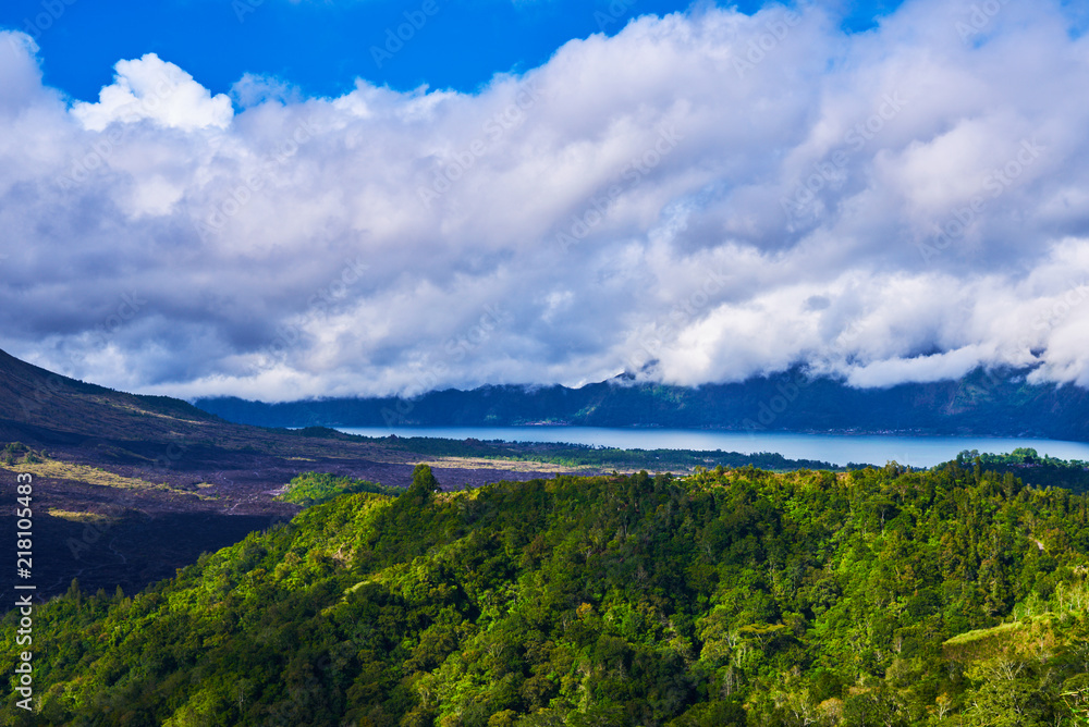 The Batur lake and volcano are in the central mountains in Bali, Indonesia. Beautiful natural landscape in the summer time. Mountains under clouds in the sun day. Natural background. Landscape.