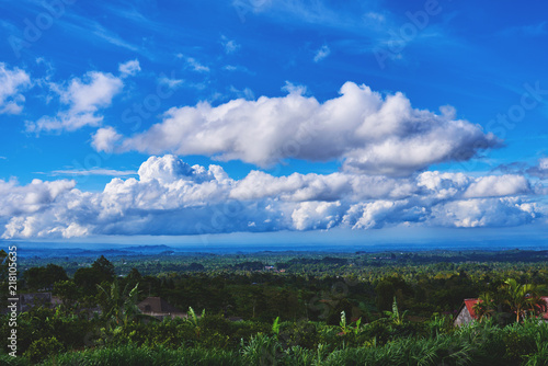 Beautiful spring or summer landscape. Nature wallpaper, background. Green hills and blue sky with white clouds. Landscape of a picturesque green tropical valley. Colourful travel background.