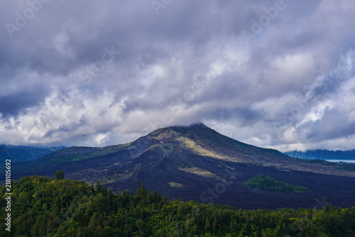 Travel background. Rural sunrise landscape. Countryside and green tropical forest. Natural background. Landscape of Batur volcano on Bali island, Indonesia. Dramatic sky with clouds in the mountains.