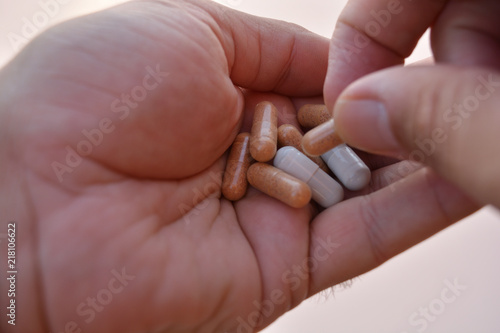 Mano mostrando un cóctel de diferentes medicamentos para el tratamiento de enfermedades como el VIH o simplemente como complementos alimenticios o adelgazamiento