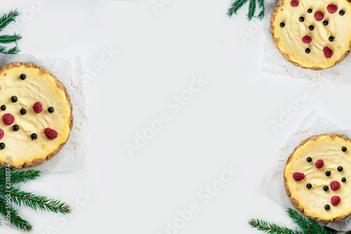 Classic Festive Christmas cheesecake on a light wooden background with Christmas tree. Christmas white chocolate cake with mascarpone. Traditional winter cake recipe. Сelebration background. 