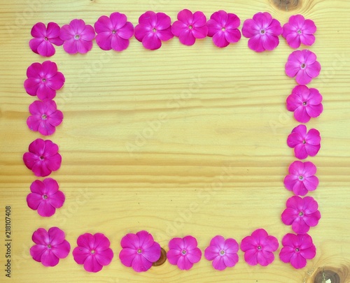Concept of a frame made by pink flowers on wooden background with copy space
