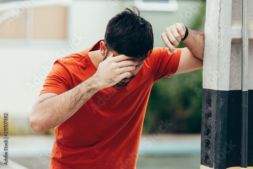 Man suffering from dizziness with difficulty standing up while leaning on wall photo