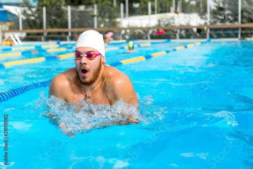 Man in swimming goggles swimming breaststroke in outdoor pool