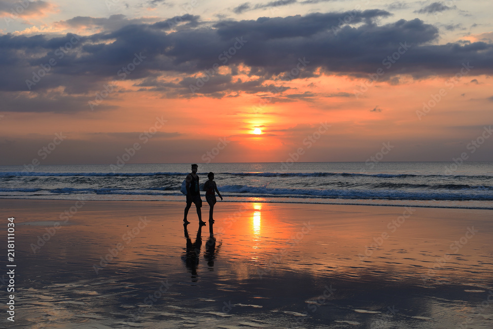 Teen boys surfers walking on beach at sunshine sunset back light. Happy childs  in the sea. Summer vacation and healthy lifestyle concept.