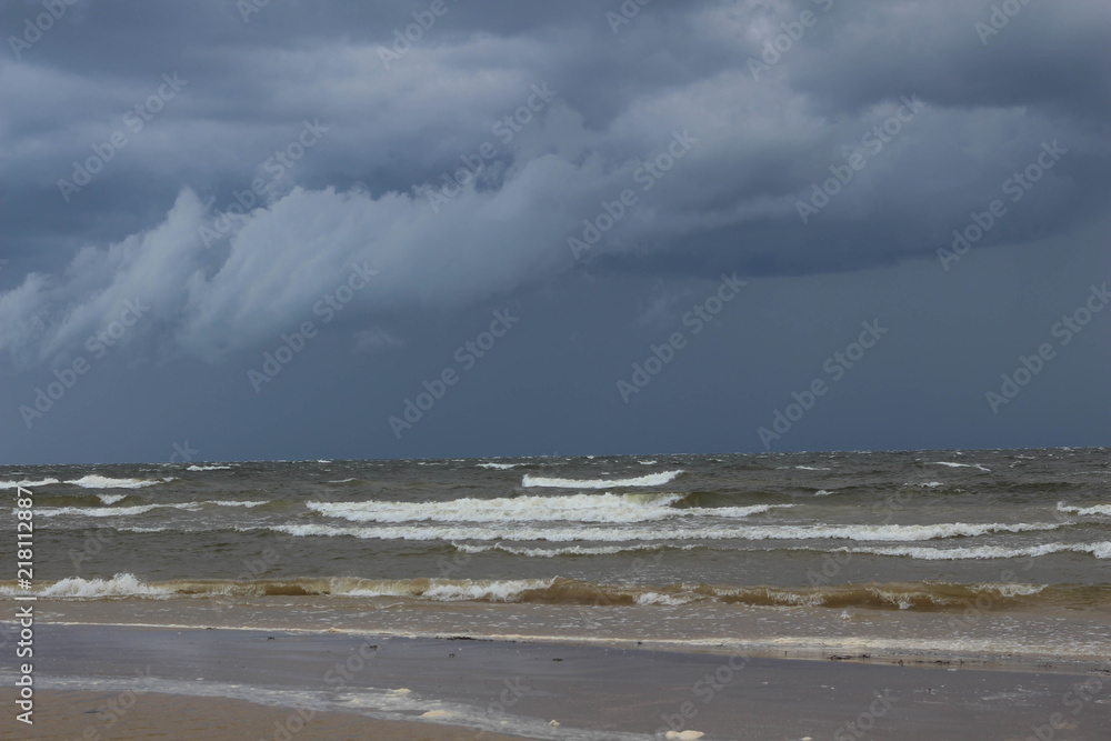 Baltic Sea. Summer. Dramatic storm clouds over the sea. Sea waves on the beach