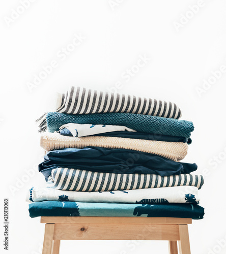 Towels  blankets and other home textile in blue and beidge colors are folding on the stool