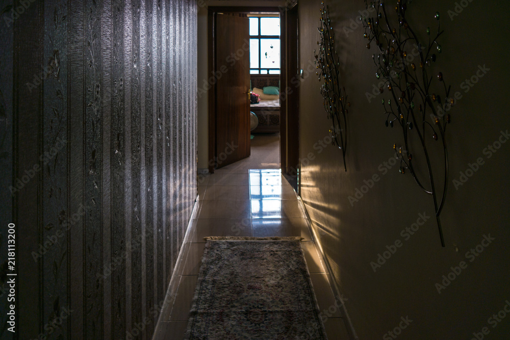 Obraz premium Dark long hallway with view of a room and light coming from the window
