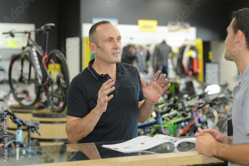 man working in bike rental shop talking to customer photo