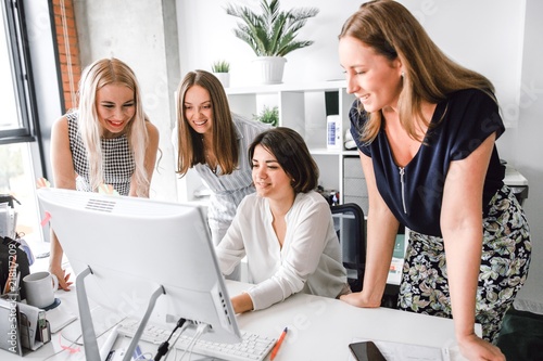 Women's team standing at the same table working at the computer photo