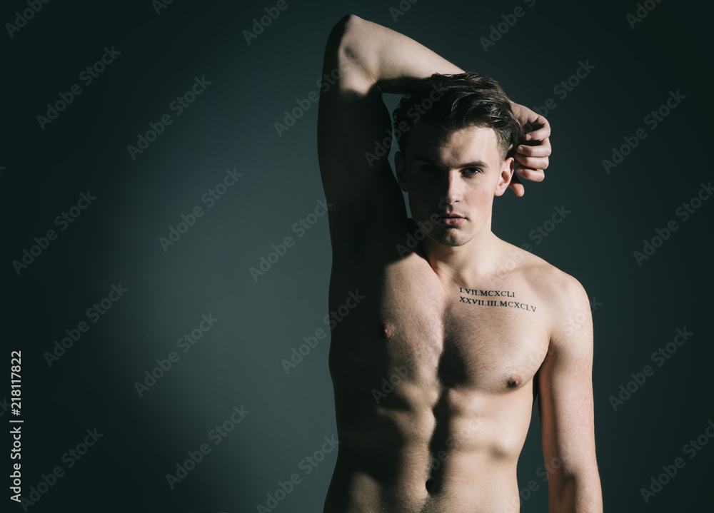 Man with torso, muscular macho with six packs, dark background. Guy with tattoo looks confident and attractive. Sexy macho concept. Macho on pensive face with muscular figure, sportsman, bodybuilder. Man with torso, muscular macho with six packs, dark background. Guy with tattoo looks confident and attractive. Sexy macho concept. Macho on pensive face with muscular figure, sportsman, bodybuilder.