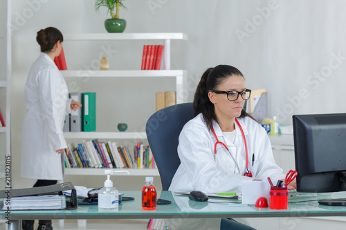 female doctor working on computer and coleague in the background photo