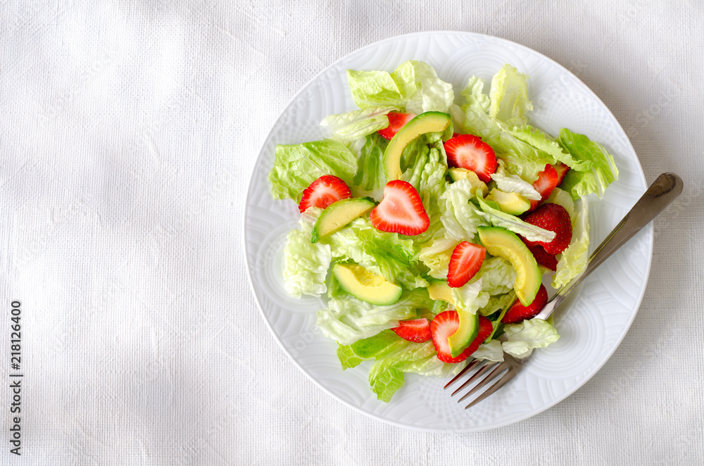 Salad with avocado, strawberries and lettuce on white background