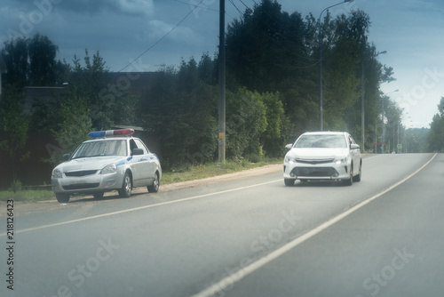 Police car on the roadside. Rural asphalt road with a white car photo