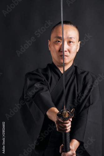 Asian man in black kimano raised his sword